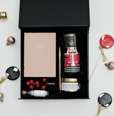 an open gift box filled with various items like wine, candles and other holiday decorations