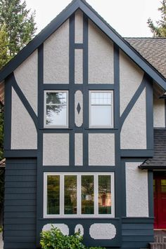 a large gray and white house with two windows on the side of it's face