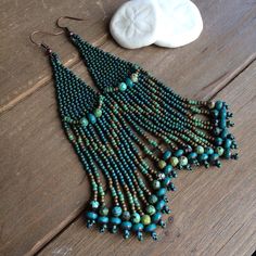 a pair of turquoise beaded earrings sitting on top of a wooden table