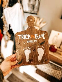 a person holding up a wooden sign that says trick or treat smell my feet on it