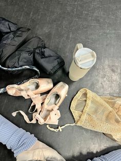 several pairs of ballet shoes are sitting on the floor next to an umbrella and trash can