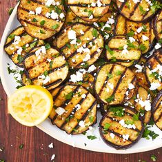 grilled eggplant with feta cheese and lemon on a white platter