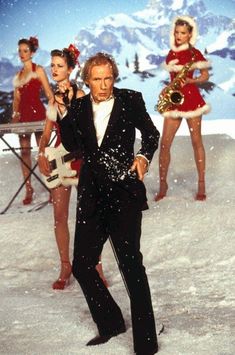 a man in a suit and some other people wearing santa hats on snow covered ground