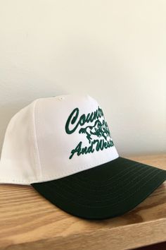 two-tone evergreen + cream trucker hat with embroidered lettering + adjustable snapback Vintage White Snapback Hat With Letter Print, Vintage White Trucker Hat With Letter Print, Vintage White Trucker Hat With Embroidered Logo, Vintage White Trucker Hat For Baseball Season, White Retro Baseball Cap With Letter Print, White Retro Snapback Hat With Embroidered Logo, Embroidered Lettering, Country And Western, Sales Gifts