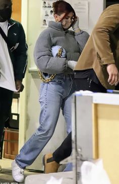 a woman in grey sweater and jeans walking through an office building with her hands on her hips