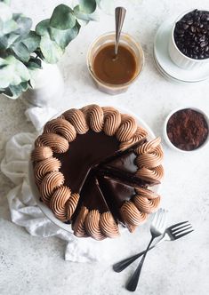 a chocolate cake sitting on top of a white plate next to two cups and spoons