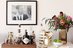 a bar with alcohol bottles and flowers in vases on the counter next to it