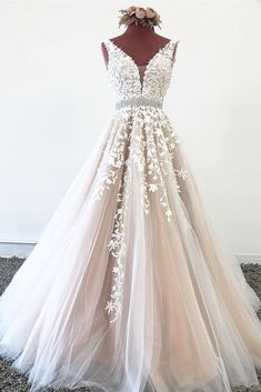 a wedding dress on display in front of a white wall, with an open back and floral appliques