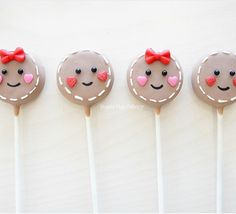 four chocolate lollipops with faces and hearts on them are lined up in a row