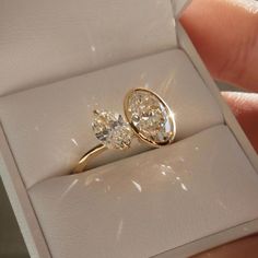 a close up of a person's hand holding an engagement ring in a box