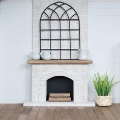 a white fireplace with a potted plant and vases on the mantle next to it