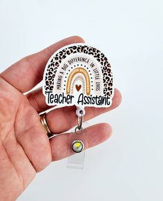 This cute Teacher Assistant rainbow Badge Reel measures aprox 2 inches. It is printed on a hard accrylic. And is attached to a retractable badge reel which is available in Alligator Clip, Belt Clip, or Lanyard with your choice of beads Teacher Badge Lanyard, Teacher Badge Reel, Badge Reels Diy, Teachers Office, Rainbow Badge, Clip Belt, Gifts For Nurses, Teacher Badge, Badge Lanyard