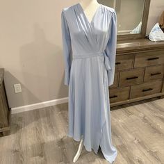 a light blue dress on display in front of a dresser with a mirror behind it