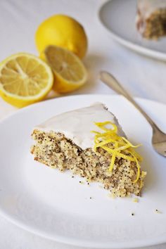 a piece of cake on a white plate with lemons and a fork next to it