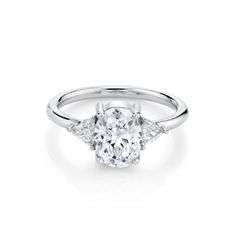 an oval diamond ring with three pear shaped diamonds on the band and side stones in white gold