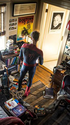 a person in a spiderman costume is standing on the floor next to a bookshelf