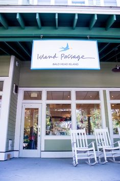 two white rocking chairs sitting in front of an island passage building with the words island passage on it