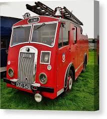 an old red firetruck parked in the grass with its ladder on it's roof