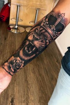 a man's arm with a lion and crown tattoo on the forearm, in black ink