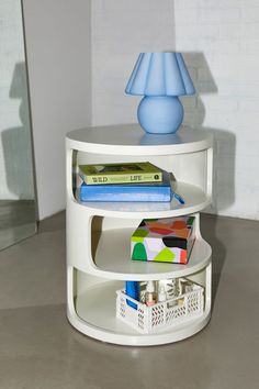 a white shelf with books and a blue lamp on top