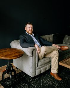 a man is sitting on a couch with his legs crossed and feet crossed, in front of a coffee table