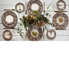 an overhead view of a table setting with plates and flowers on the wall behind it