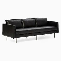 a black leather couch sitting on top of a white floor next to a metal frame