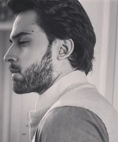 a black and white photo of a man with ear piercings looking off to the side