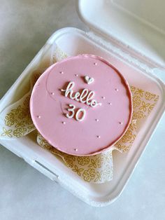 a pink cake in a plastic container with hello 50 written on the top and white frosting