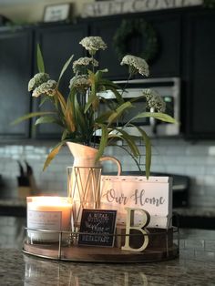 candles and flowers in a vase sitting on a counter top next to a sign that says our home