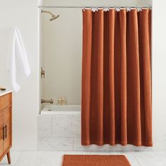 an orange shower curtain in a bathroom next to a white bathtub and wooden cabinet