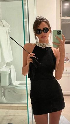 a woman taking a selfie in front of a mirror with her cell phone and wearing sunglasses