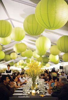 many people are sitting at tables with paper lanterns hanging from the ceiling