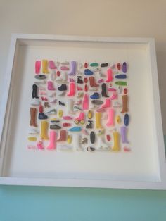 a white framed artwork with different colored shoes on it's sides and feet in the middle