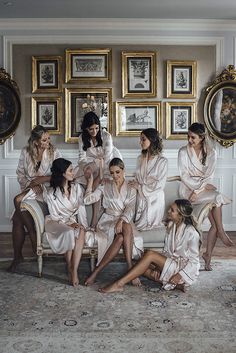 a group of women sitting on top of a couch in matching bathrobe outfits