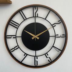 a black and gold clock with roman numerals on the side of a wall