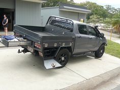 a truck is parked in front of a garage with a woman standing next to it