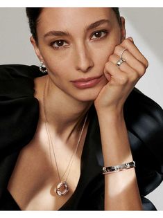 a woman with her hand on her chin wearing rings and bracelets, posing for the camera