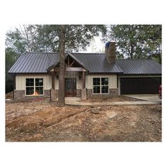 a house with two windows and a metal roof in the middle of an area that is under construction