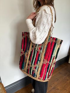 a woman is holding a multicolored bag