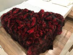 a red and black heart shaped rug sitting on top of a wooden floor next to a bed