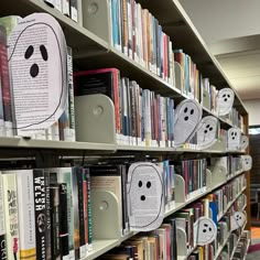 several books are on shelves in a library with ghost faces drawn on the book covers