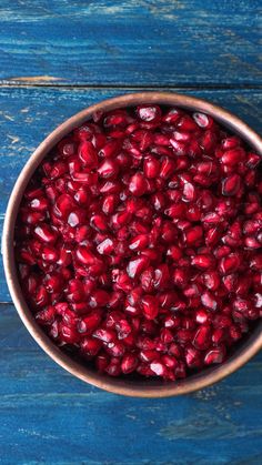 a bowl full of pomegranate sitting on top of a blue wooden table