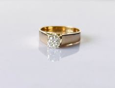 a gold and diamond ring on a white surface, with the center stone in the middle