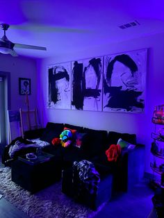 the living room is lit up with purple lighting and black couches in front of paintings