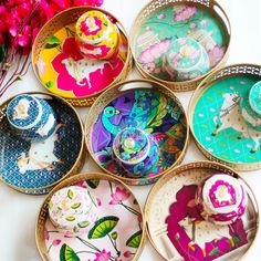 six colorful plates with designs on them and flowers in the background