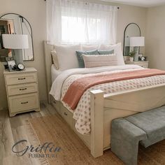 a bedroom with a bed, mirror and bench in the corner on the floor next to the window