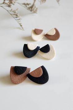 three different shapes of black, white and brown stones on a table next to a plant