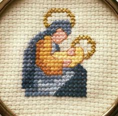 a cross stitched picture of a person holding a baby