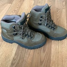 a pair of gray boots sitting on top of a wooden floor